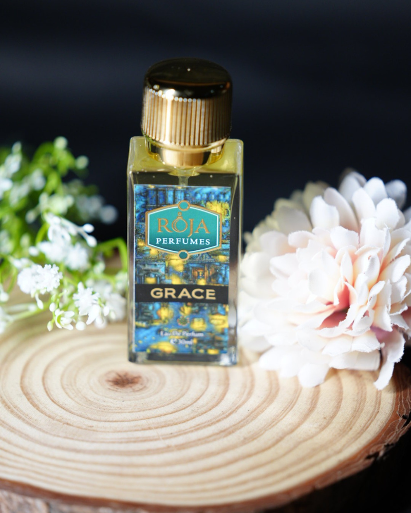 Roja Fume Grace perfume bottle on a wooden slice with flowers