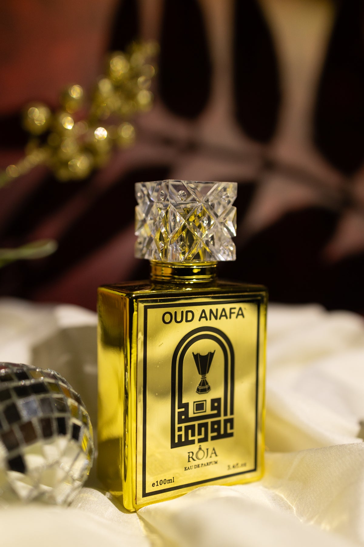 Roja Fume Oud Anafa 100ml gold perfume bottle on dark fabric